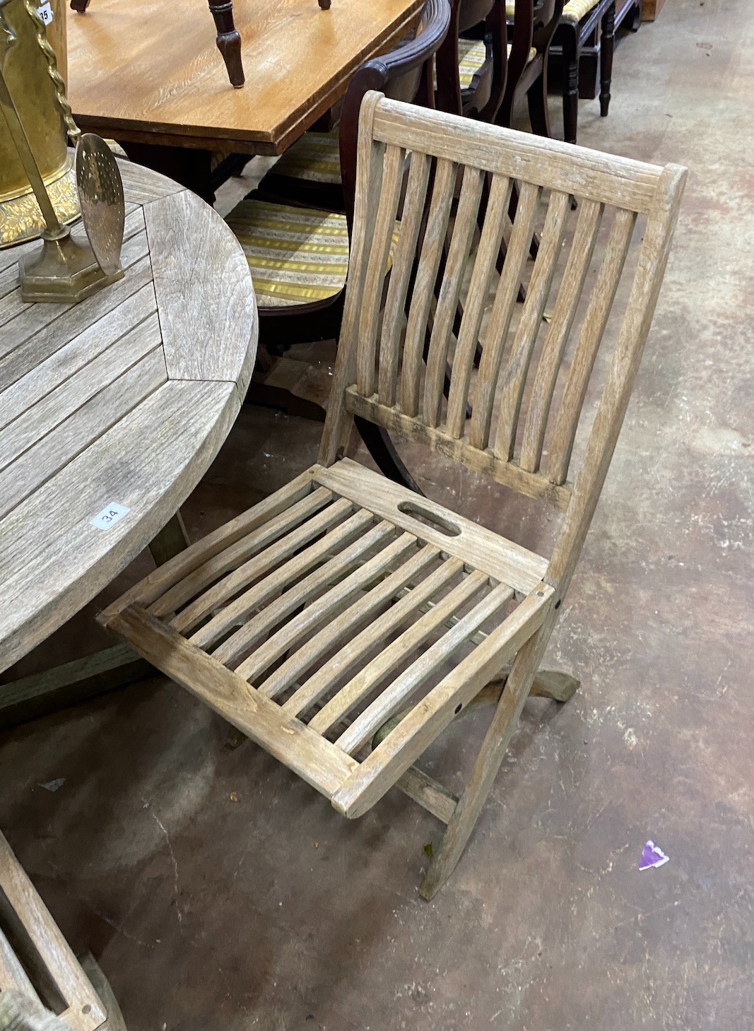 A Gloster weathered teak circular garden table, diameter 130cm, height 70cm and four folding chairs